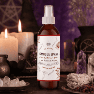 Amber smudge spray bottle on a wooden altar with candles and crystals